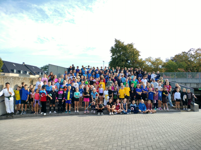 Grote groep kinderen poseert met kledij van de sportclubs