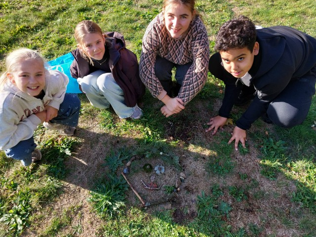 Kinderen maken een kunstwerk van takken en blaadjes. 